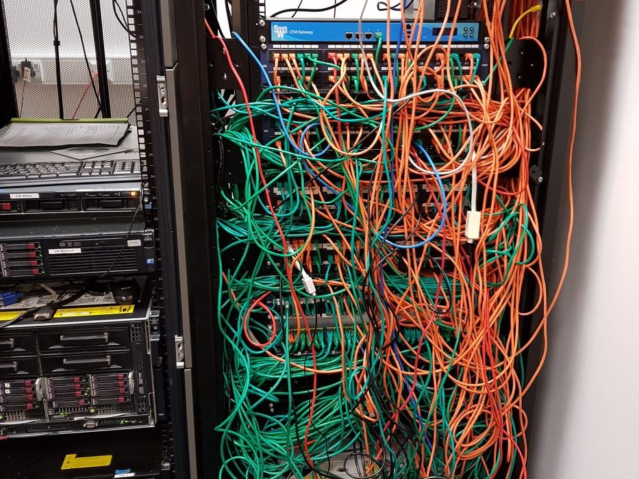Disorganised server cabinet with tangled cables before Forge42 organisation